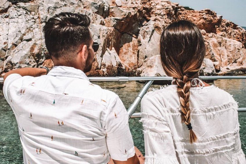 Una pareja de pie junto a una costa rocosa con vista despejada al agua. 5