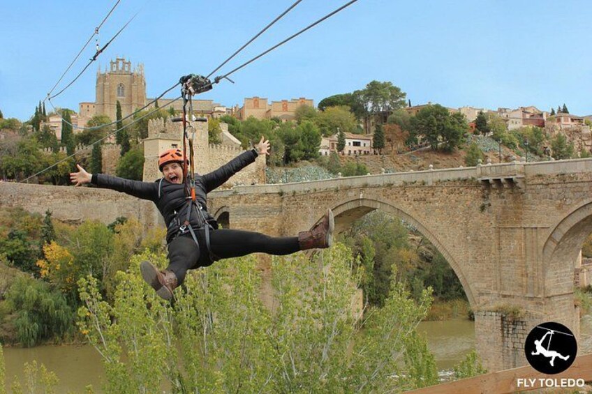 A person bungee jumping with a bridge and historic buildings in the background. 1