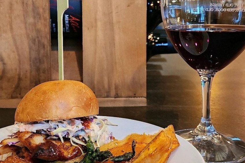 A plate with a sandwich, coleslaw, and fries, and a glass of red wine. 4