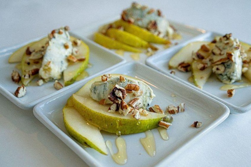 A plate of food with a blue cheese topping and nuts on a green apple slice. 3
