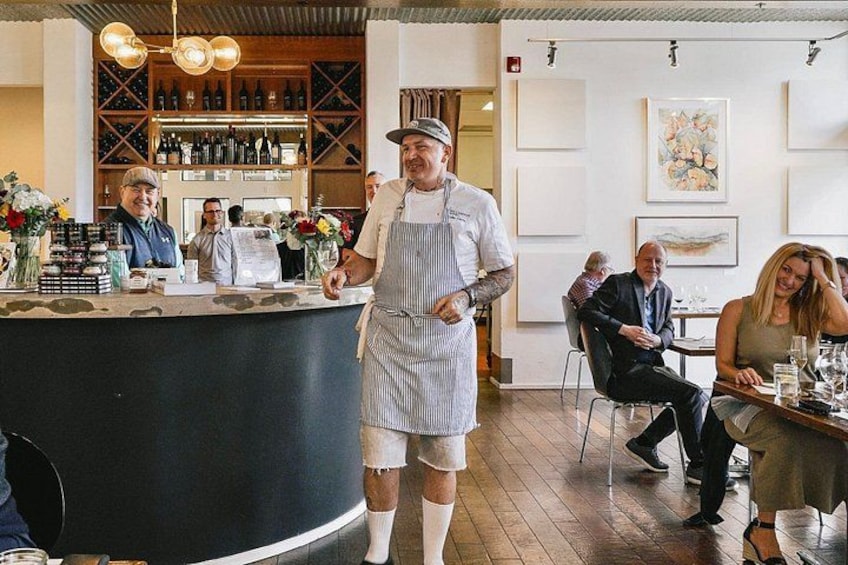 A restaurant interior with a bar area, wooden flooring, and a person in a chef's uniform standing at the bar. 5