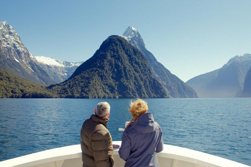 Two people on a boat facing a mountainous landscape with a lake. 5