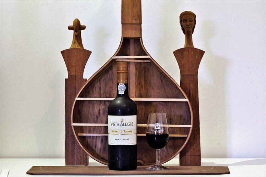 Una botella de vino Vista Alegre y una copa sobre un soporte de madera. 2
