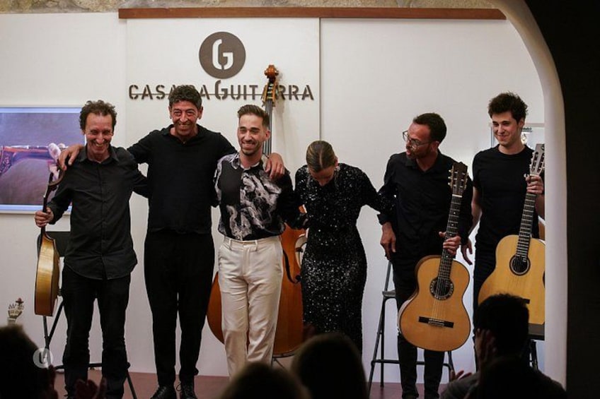 En gruppe mennesker holder guitarer foran en væg med teksten 'CASA DE GUITARRA'. 3