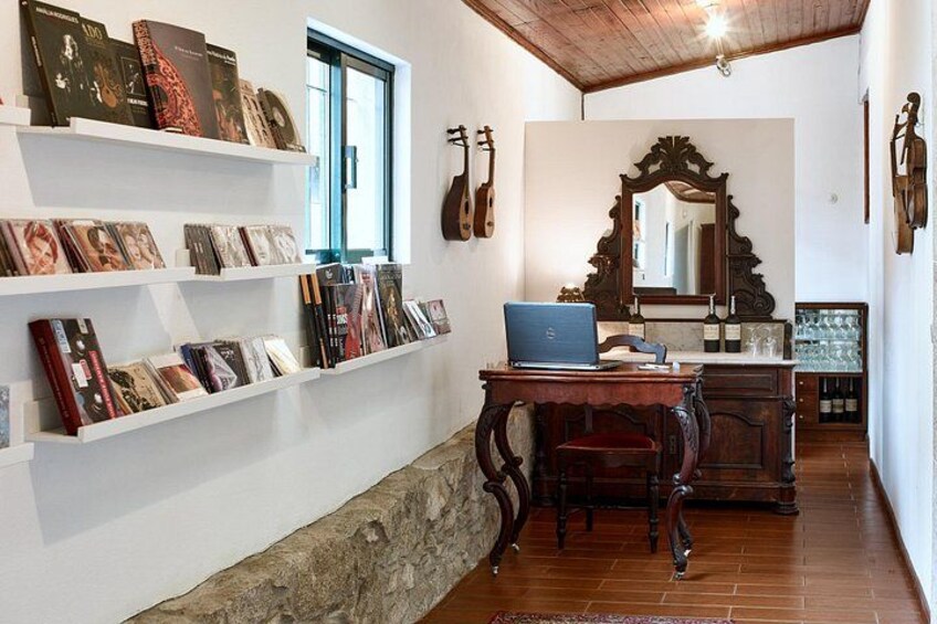 Une pièce avec des étagères à livres, un bureau en bois, un ordinateur portable, une guitare, un miroir et un mur en pierre. 5
