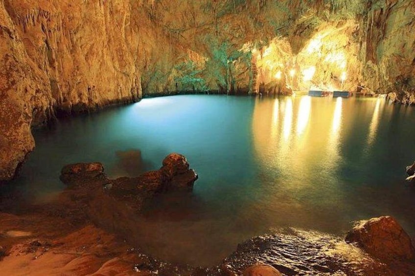Eine Höhle mit einem ruhigen Becken, beleuchtet durch künstliches Licht, und steinernen Felsformationen. 2