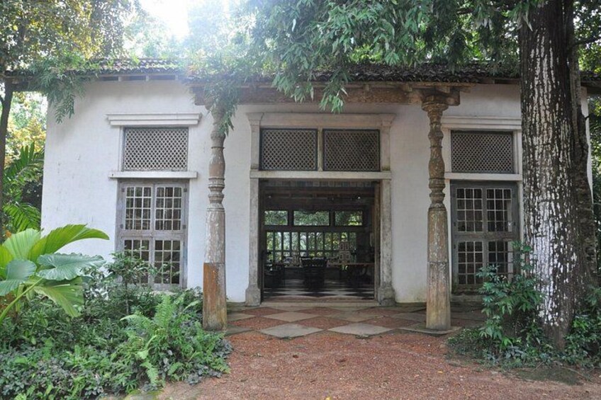 Un edificio tradicional con un porche cubierto, rodeado de abundante vegetación. 1