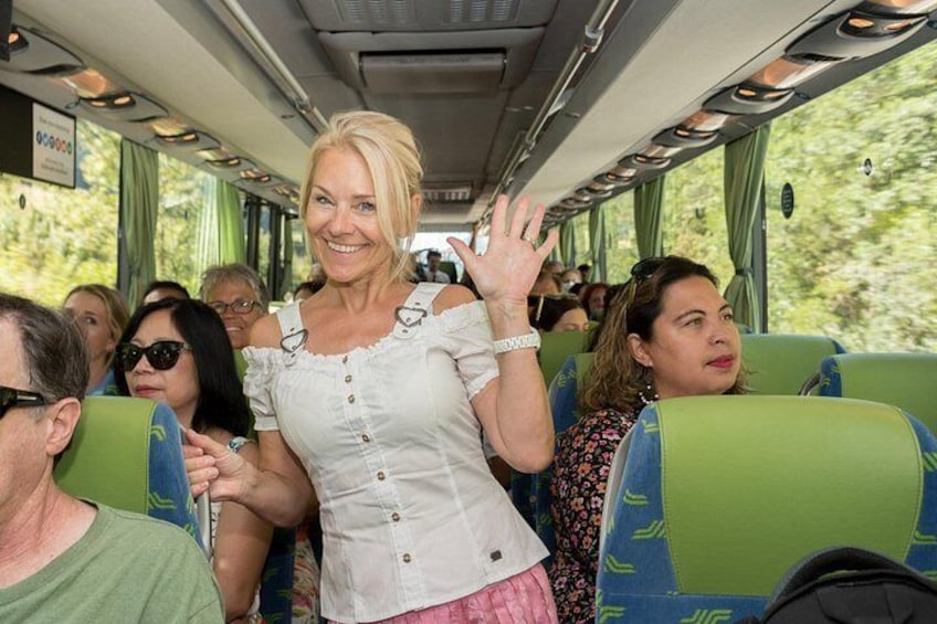Interior de autobús con pasajeros sentados y una persona de pie, saludando. 5