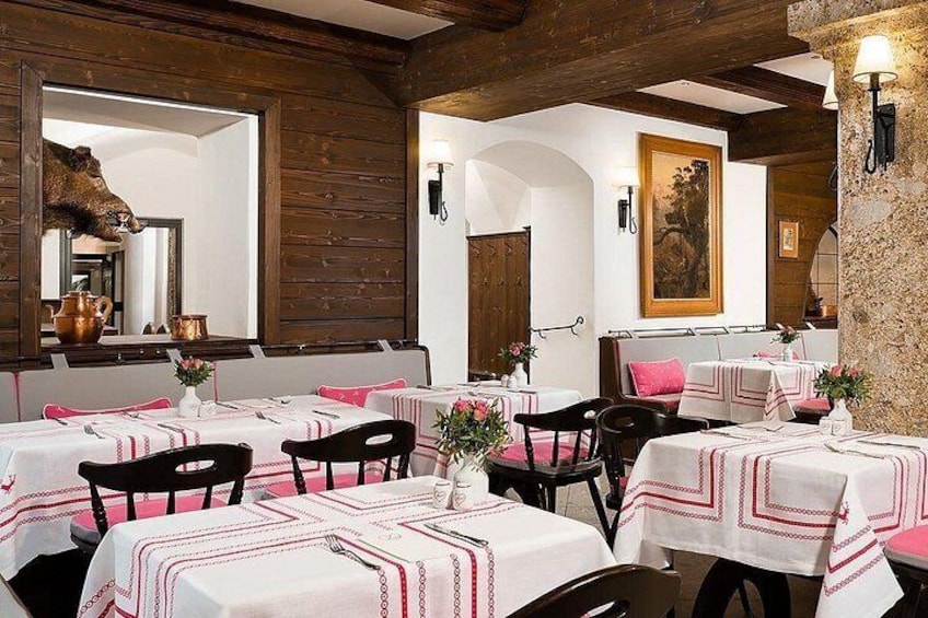 Interior de restaurante con vigas de madera, mesas blancas con manteles rojo y blanco, y sillas negras. 4