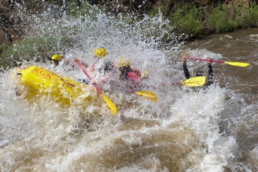 A white water rafting scene with kayakers in yellow and pink kayaks navigating through rapids. 4