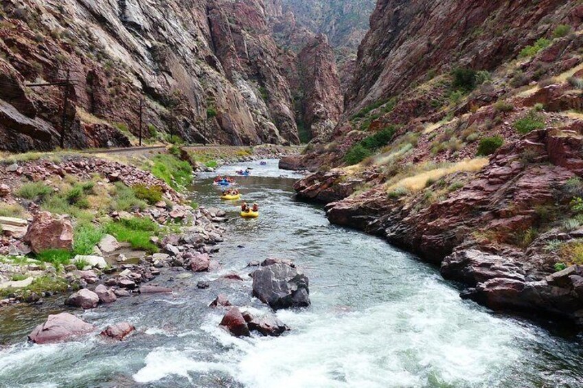 A river with rapids, surrounded by rocky cliffs and greenery. 3