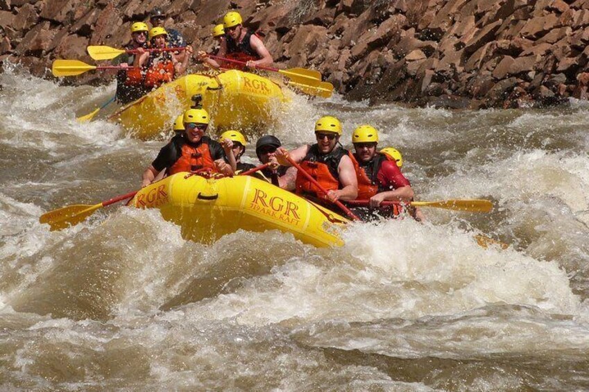 A group of people in yellow inflatable rafts navigating a river. 2