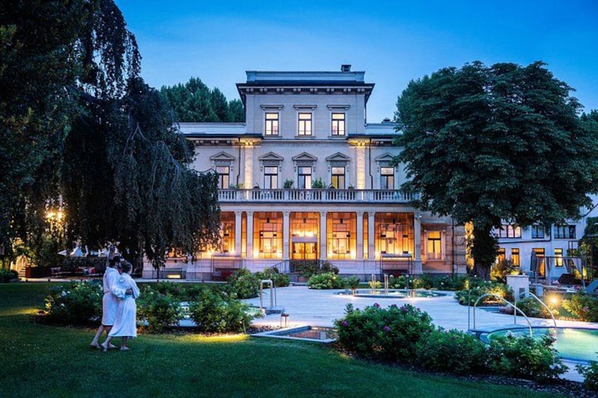 A large, elegant building with a formal garden and a well-lit entrance. 1