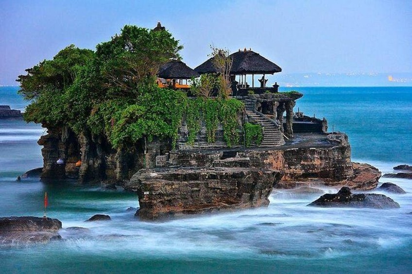 A rocky island with a gazebo and a staircase leading up to a structure surrounded by lush greenery. 1