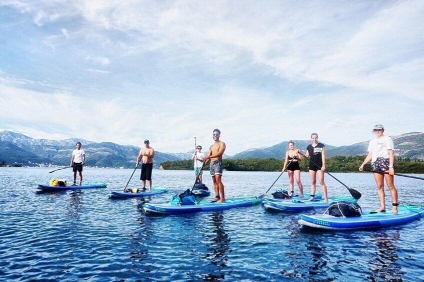 Folk padler på paddleboards på en rolig sø med bjerge i baggrunden. 3
