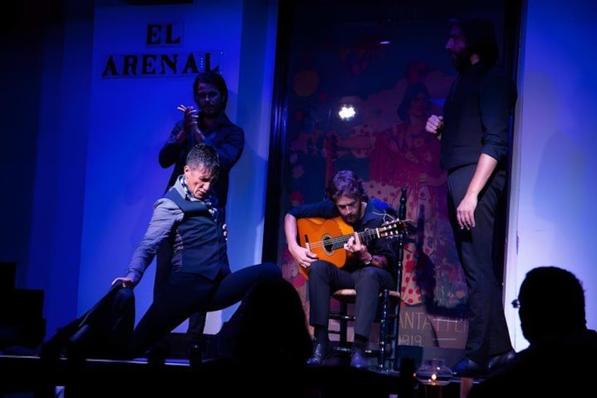 A stage with a person playing guitar, another person standing, and a third person clapping. 5