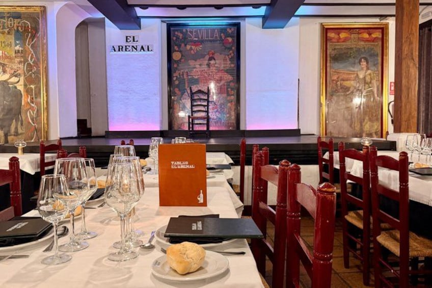 A restaurant interior with tables set for dining, red chairs, and a menu stand. 4