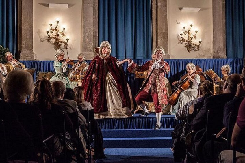 En historisk teater med utsmyckade dekorationer, en scen och en publik. 2