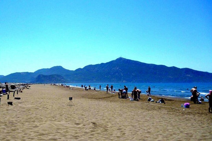 Een strand met mensen, een camera op een statief en bergen op de achtergrond. 4
