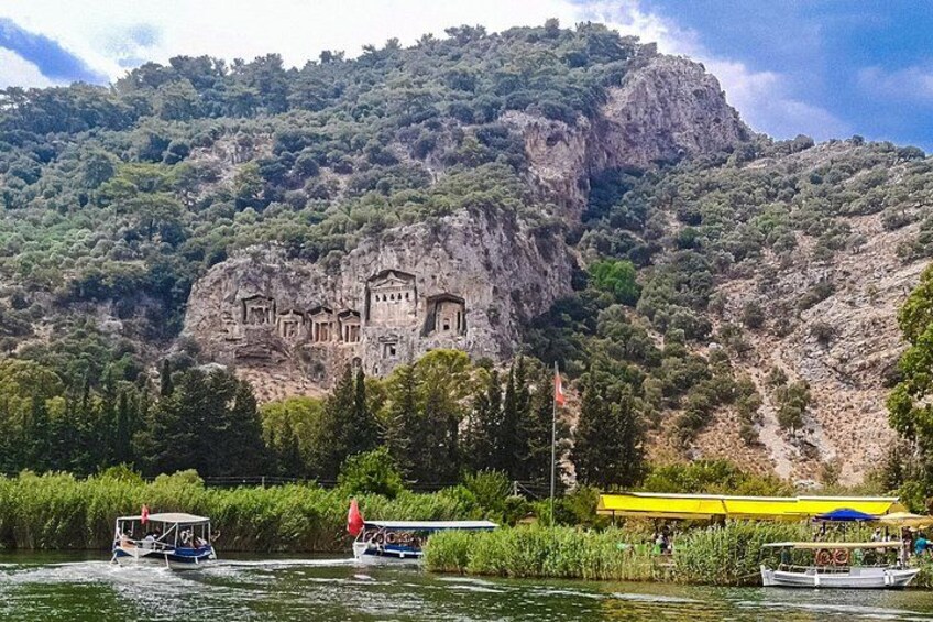 A rocky mountain with ancient ruins, a river with boats, and a yellow canopy. 3