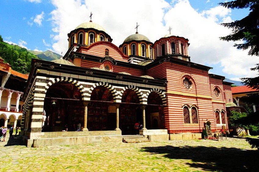 A red and white striped building with domed roofs, a courtyard, and a cobblestone ground. 3
