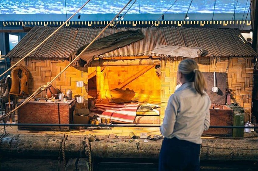 Eine Person betrachtet eine traditionelle Schmiede mit Feuer, Holzbauten und Werkzeugen. 3