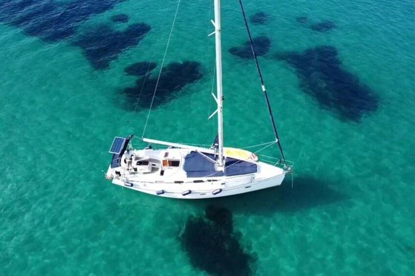 A sailboat anchored in clear turquoise waters with visible coral formations. 5