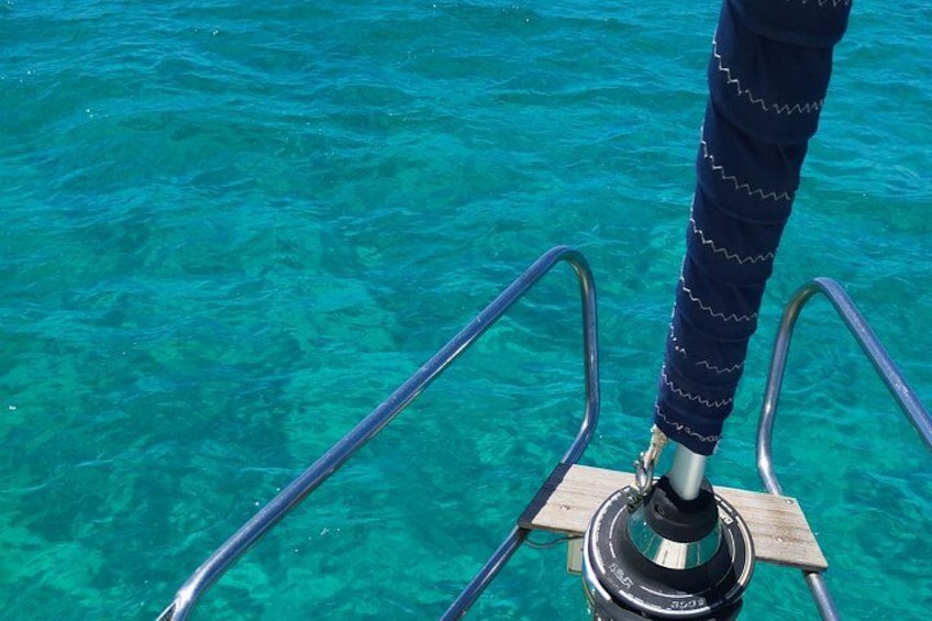 A metal ladder leading into turquoise water, with a wooden platform and a metal railing. 3