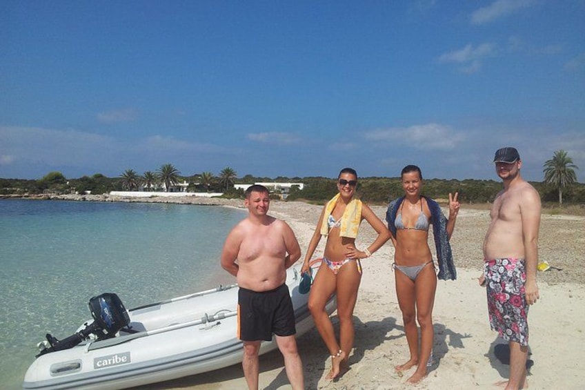 Een strand met helder water, een boot en mensen in zwemkleding. 3