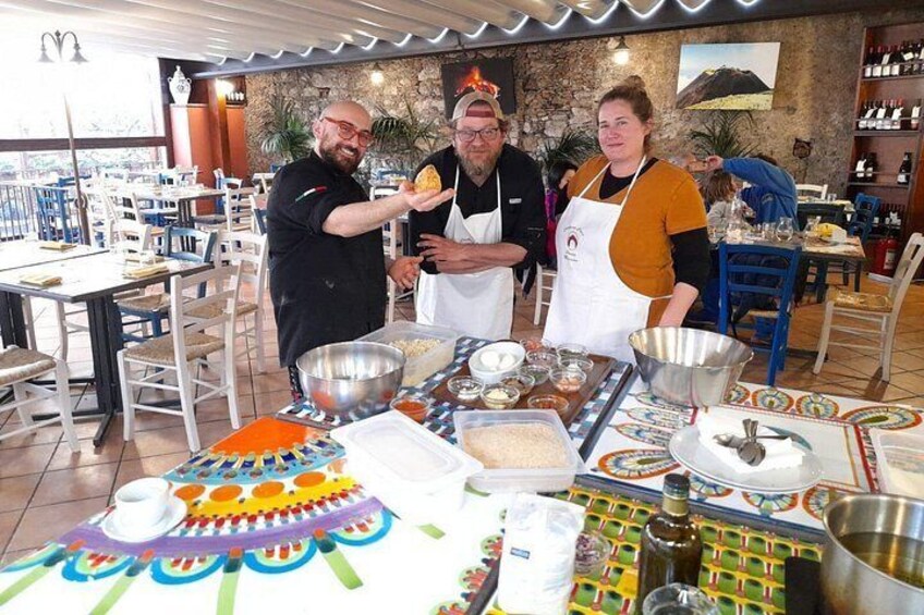 Un gruppo di persone in un ristorante, con un tavolo ricco di cibi e utensili da cucina. 1