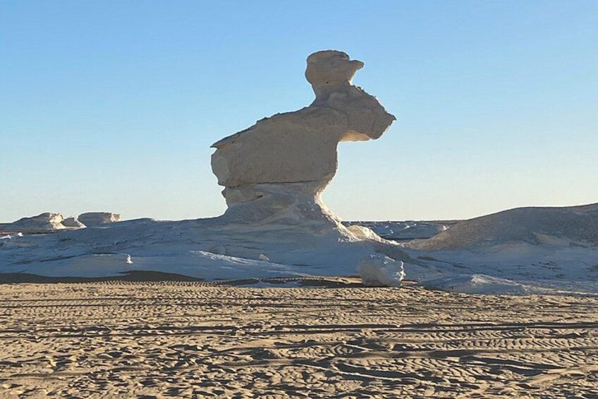 A snow-covered landscape with a prominent rock formation resembling a human figure. 5
