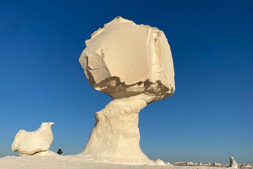 A large rock formation with a balanced, rounded top and a smaller rock nearby. 4