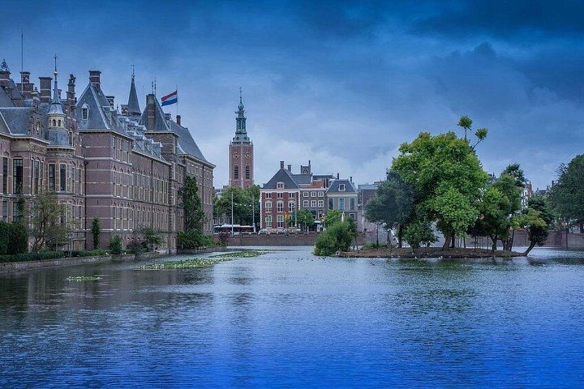 A historic building with a flag, a tower, and a river with trees. 3