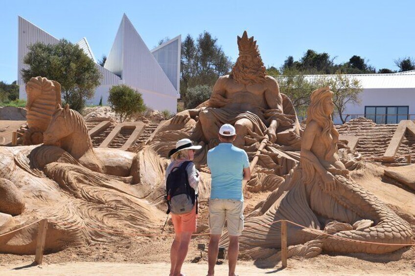 A large sand sculpture of a seated figure with a lion, a seated figure with a lion, and a standing figure with a lion. 3