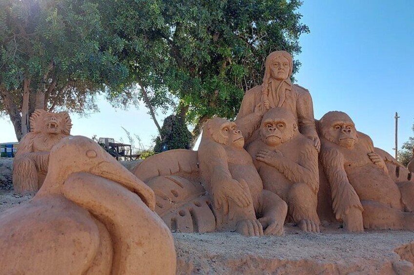 A sand sculpture of a seated figure with a child and two animals. 4