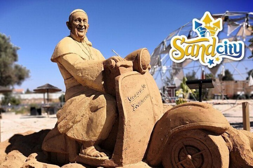 A sand sculpture of a man on a motorcycle with the text "Kensington & Westminster" on the side. 1