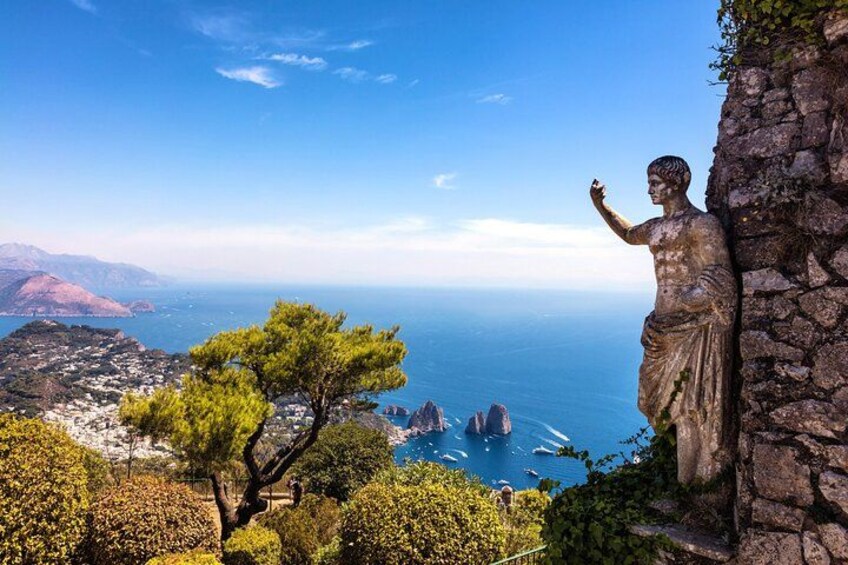 A statue overlooking a coastal landscape with a clear view of the sea and distant mountains. 2