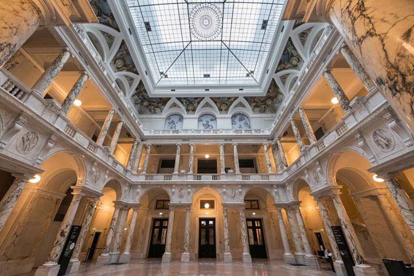 A grand atrium with a glass ceiling, marble columns, and ornate decorations. 2