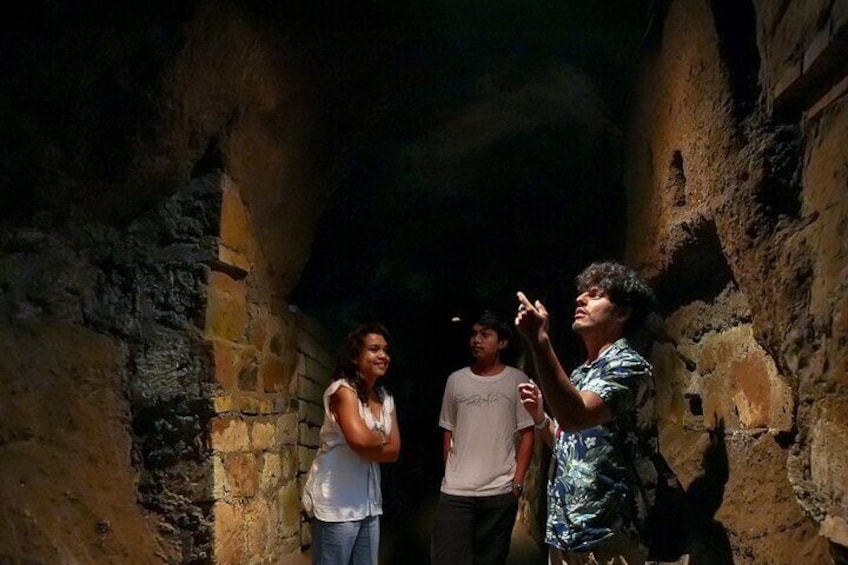Three people standing in a narrow passageway with stone walls. 5