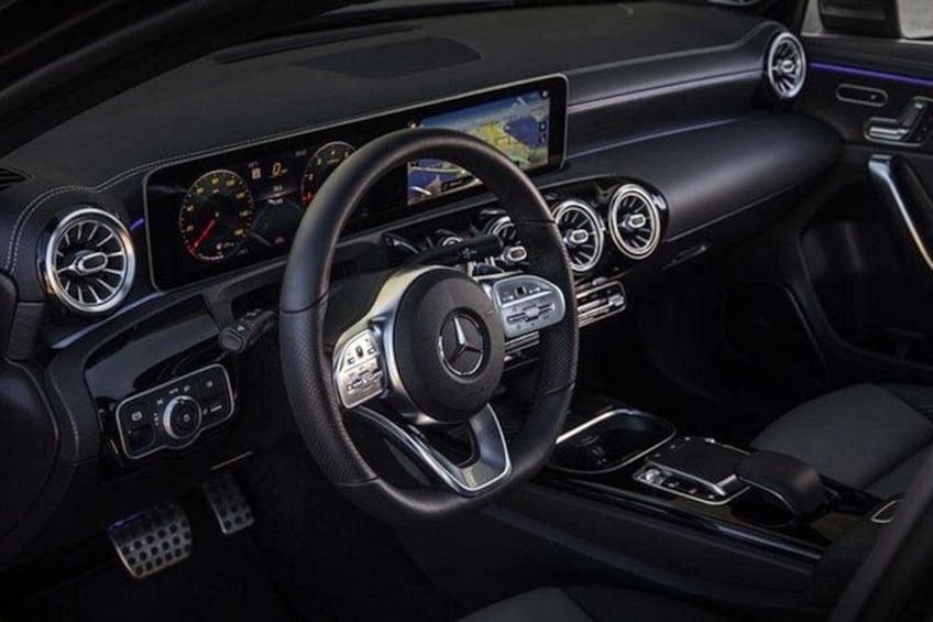 A luxury car interior with a steering wheel, dashboard, and center console. 2