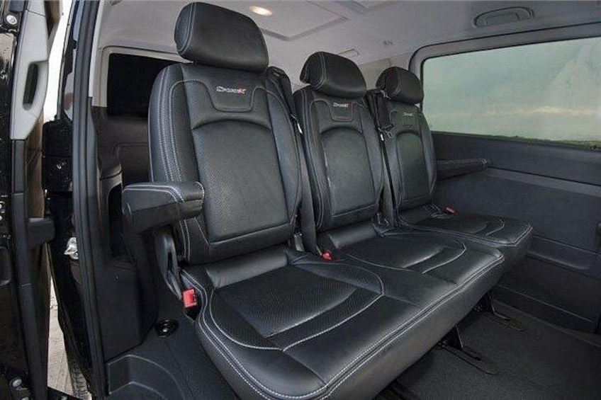 A vehicle interior with black leather seats, a central console, and a window. 3