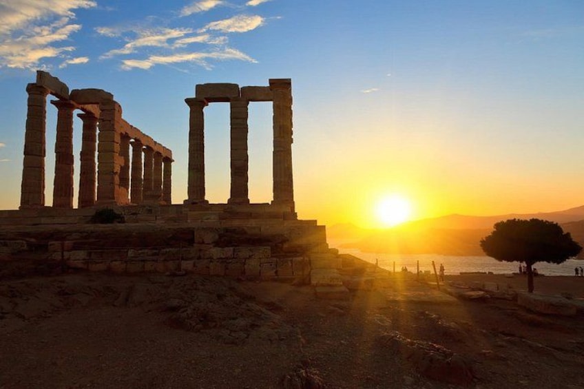 Ancient ruins with columns, a sunset, and a tree. 2