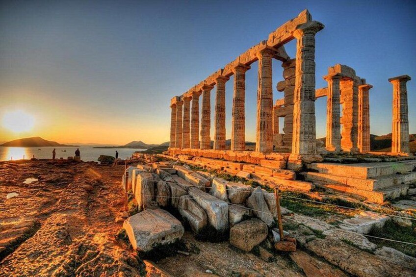 Ancient ruins with columns, a sunset, and a body of water. 3