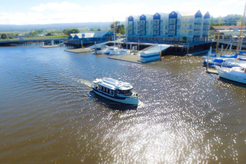 A river with a boat moving towards a marina with buildings and docks. 3