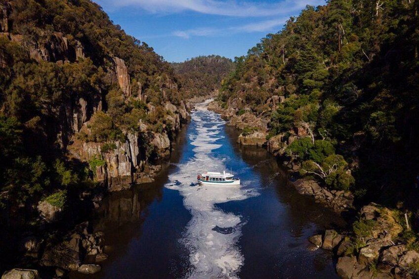 A river flanked by rocky cliffs and dense forest, with a boat navigating the water. 3