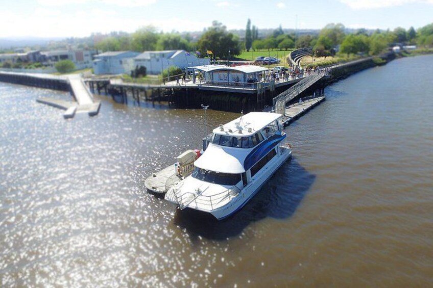 A river with a boat docked at a pier, surrounded by greenery and buildings. 4