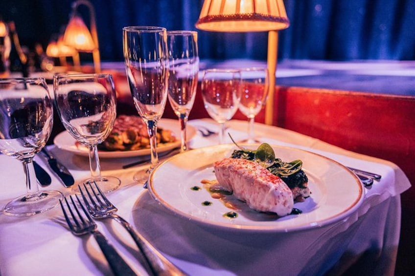 A dining table with a plate of food, wine glasses, and cutlery. 4