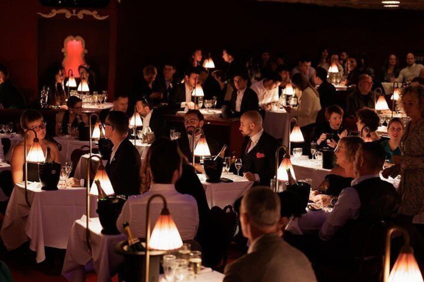 A crowded restaurant with tables and people dining. 4