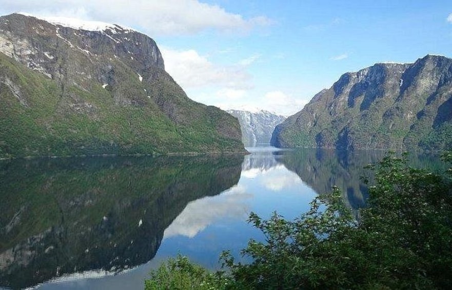 Ein ruhiger See, umgeben von steilen, bewaldeten Bergen, mit einem klaren Spiegelbild der Landschaft. 1