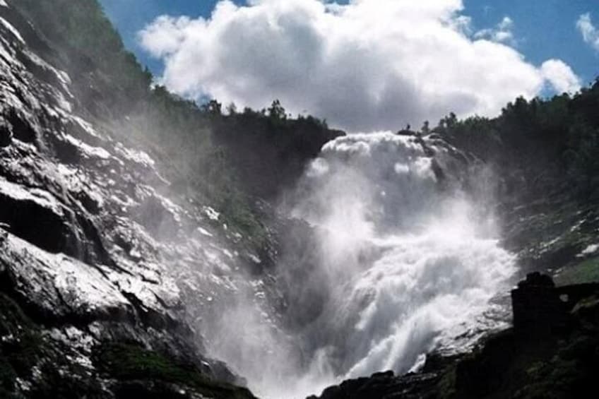 A waterfall cascading down a rocky cliff surrounded by greenery. 4